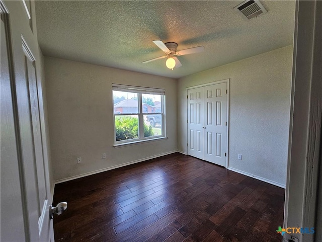 unfurnished bedroom with baseboards, visible vents, a textured ceiling, and dark wood-type flooring