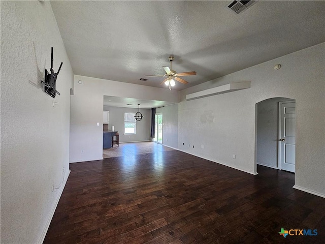 unfurnished living room featuring a ceiling fan, visible vents, a textured wall, a textured ceiling, and wood finished floors