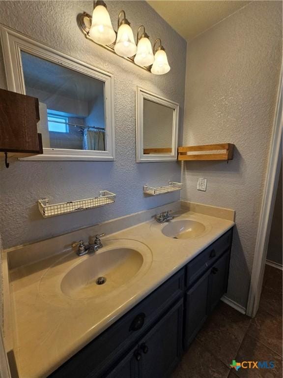 bathroom with double vanity, a textured wall, tile patterned floors, and a sink