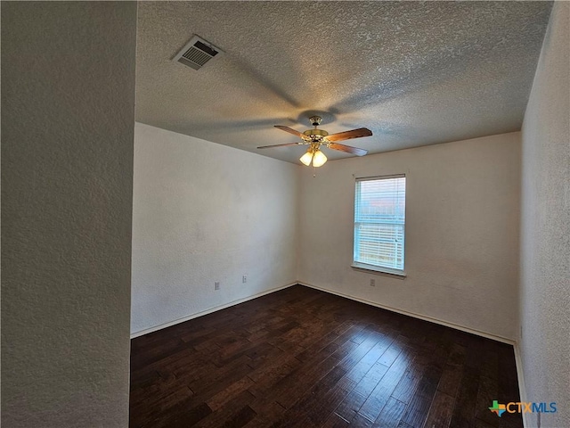 spare room with dark wood finished floors, a textured wall, visible vents, a ceiling fan, and a textured ceiling