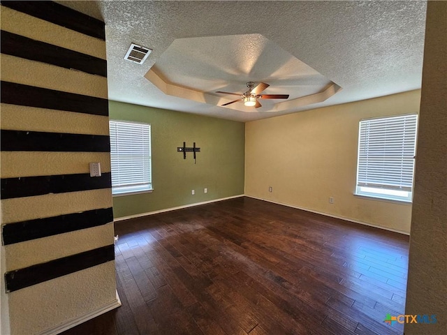 spare room with a textured ceiling, a raised ceiling, a ceiling fan, and visible vents