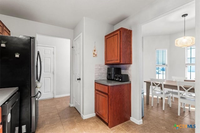 kitchen with backsplash, stainless steel refrigerator, light tile patterned floors, and pendant lighting