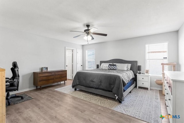 bedroom featuring multiple windows, ceiling fan, and light wood-type flooring