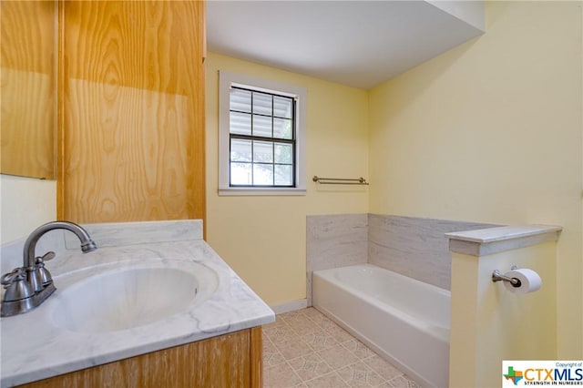 bathroom with a tub to relax in, tile patterned flooring, and vanity