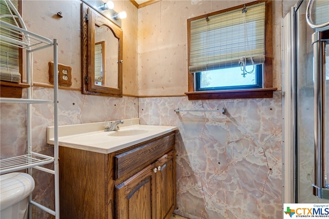 bathroom with vanity, toilet, and tile walls