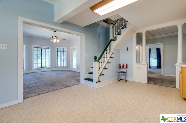 carpeted entrance foyer with ornamental molding, ceiling fan, and ornate columns