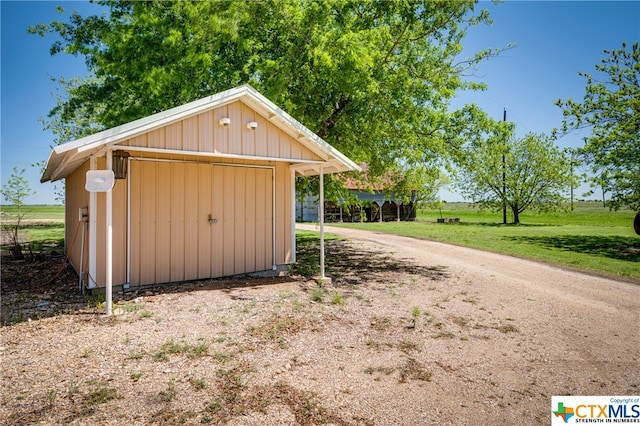 view of outbuilding featuring a garage, a lawn, and a rural view