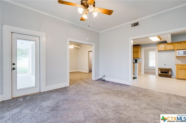 unfurnished living room featuring light carpet, crown molding, a wealth of natural light, and ceiling fan