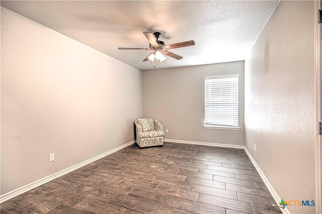 unfurnished room featuring baseboards, a ceiling fan, a textured wall, dark wood-style flooring, and a textured ceiling