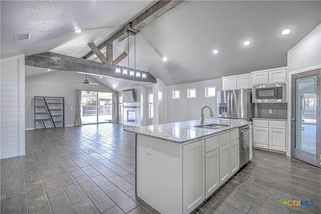 kitchen with visible vents, lofted ceiling with beams, appliances with stainless steel finishes, white cabinetry, and a sink