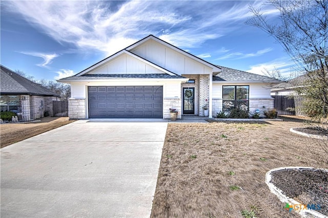 view of front facade with an attached garage, stone siding, fence, and concrete driveway