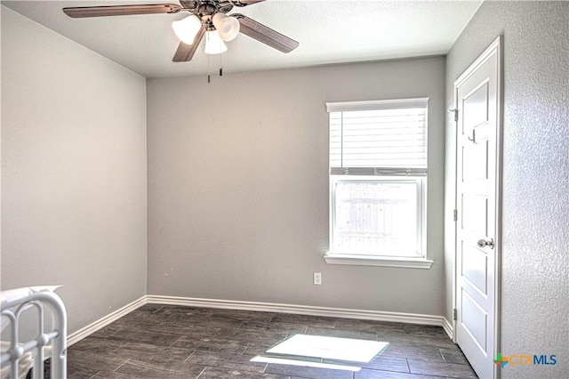 spare room featuring ceiling fan, dark wood finished floors, and baseboards