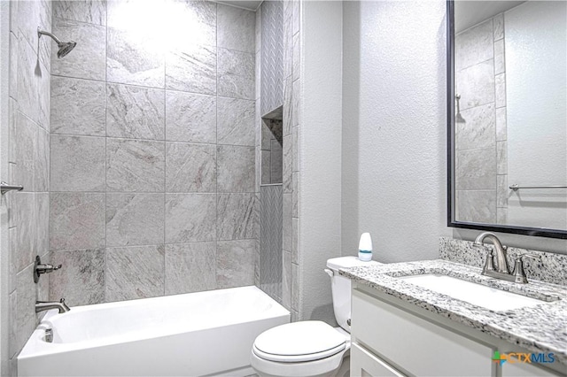 bathroom with a textured wall, shower / bathing tub combination, vanity, and toilet