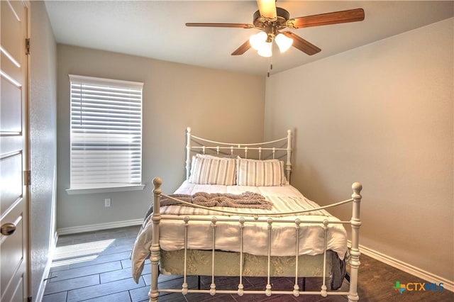 bedroom with a ceiling fan, baseboards, and wood finished floors