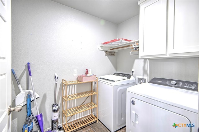 laundry area with cabinet space, washing machine and dryer, and a textured wall