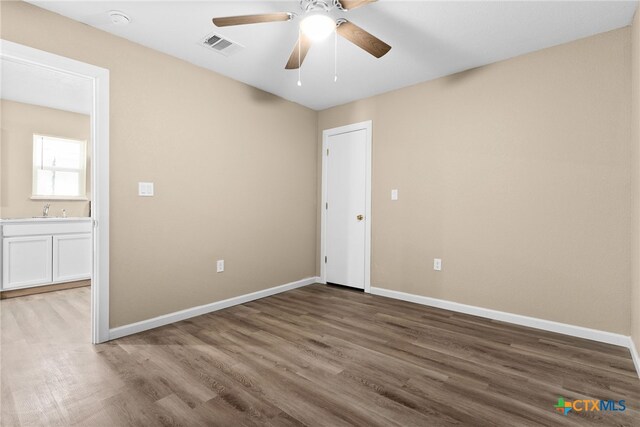 empty room featuring ceiling fan, sink, and wood-type flooring