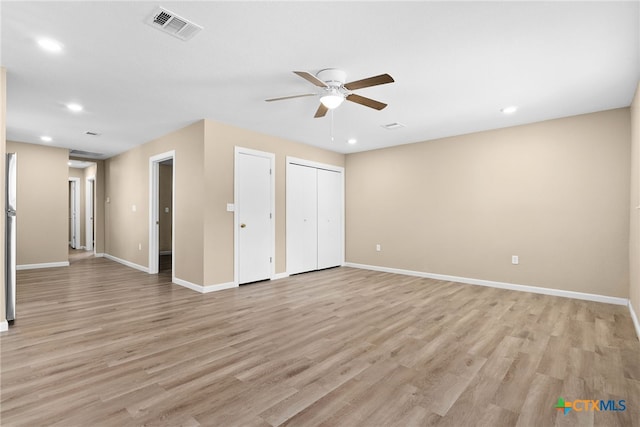 unfurnished bedroom featuring multiple closets, ceiling fan, and light wood-type flooring