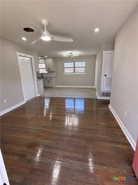 unfurnished living room featuring dark hardwood / wood-style floors, sink, a textured ceiling, and ceiling fan