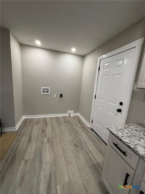 clothes washing area with cabinets, washer hookup, and light wood-type flooring