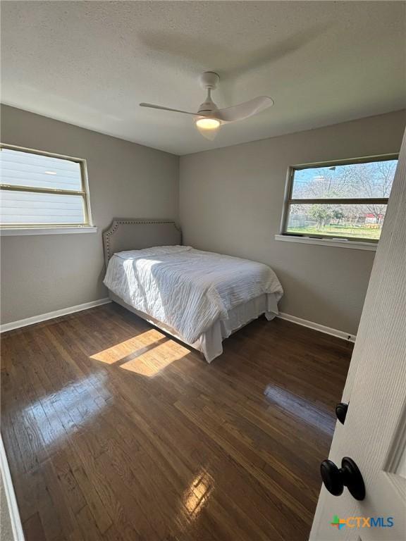 unfurnished bedroom with dark wood-type flooring, a textured ceiling, and ceiling fan