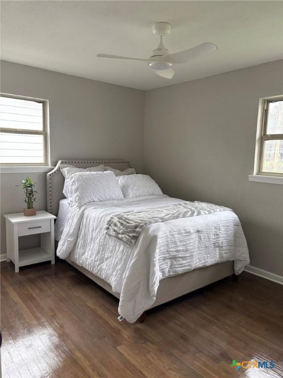 bedroom featuring multiple windows, dark wood-type flooring, and ceiling fan