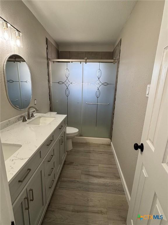 bathroom with vanity, hardwood / wood-style floors, an enclosed shower, and toilet