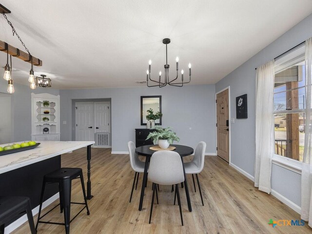 187 Meadow Ave, New Braunfels, TX 78130 - dining area featuring a notable chandelier, baseboards, and light wood-type flooring