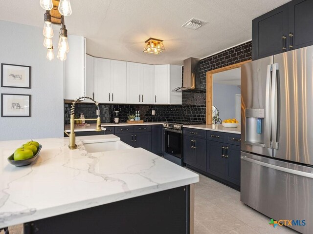 187 Meadow Ave, New Braunfels, TX 78130 - kitchen with visible vents, appliances with stainless steel finishes, white cabinetry, a sink, and wall chimney range hood