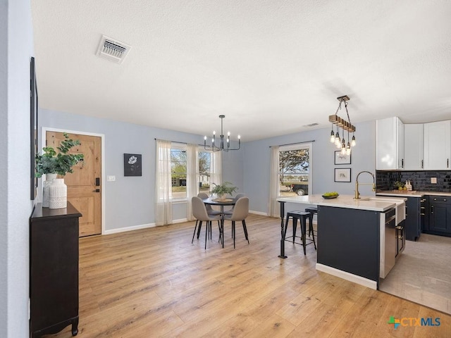 187 Meadow Ave, New Braunfels, TX 78130 - kitchen featuring light countertops, light wood-type flooring, a chandelier, backsplash, and visible vents