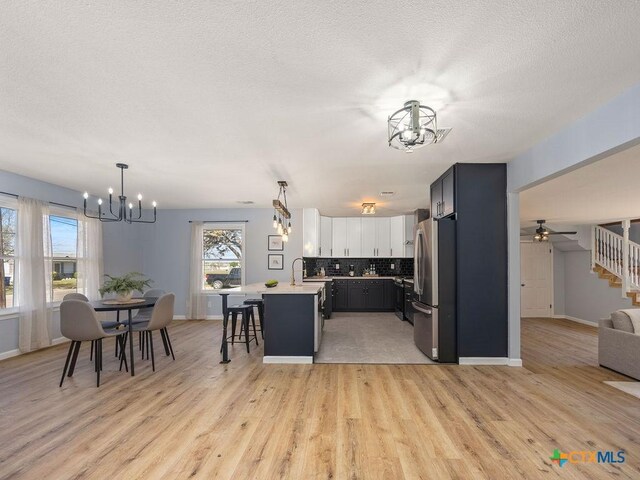 187 Meadow Ave, New Braunfels, TX 78130 - kitchen with light countertops, tasteful backsplash, a breakfast bar, freestanding refrigerator, and a notable chandelier