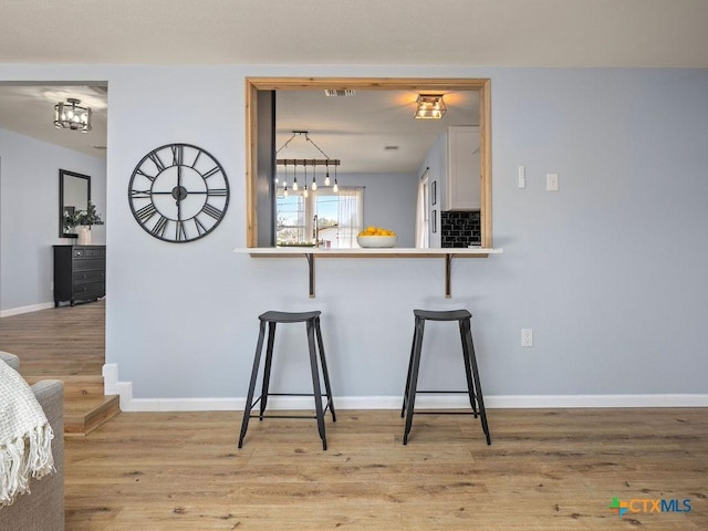 187 Meadow Ave, New Braunfels, TX 78130 - kitchen featuring baseboards, a breakfast bar area, and wood finished floors