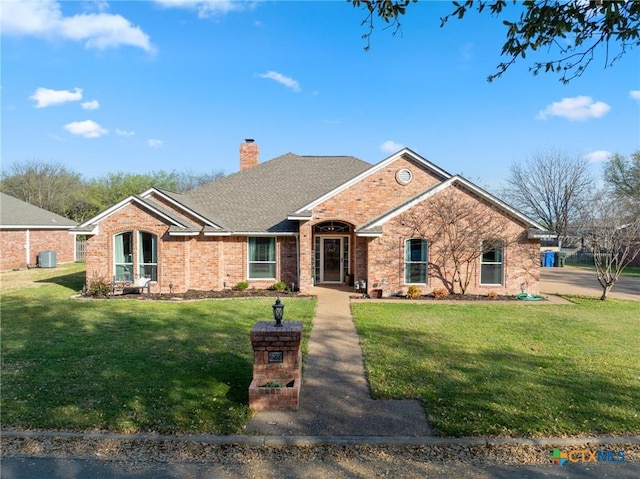 ranch-style house with a chimney, brick siding, central air condition unit, and a front lawn