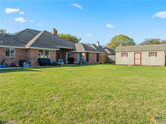 back of property featuring an outdoor structure, brick siding, a storage unit, and a lawn