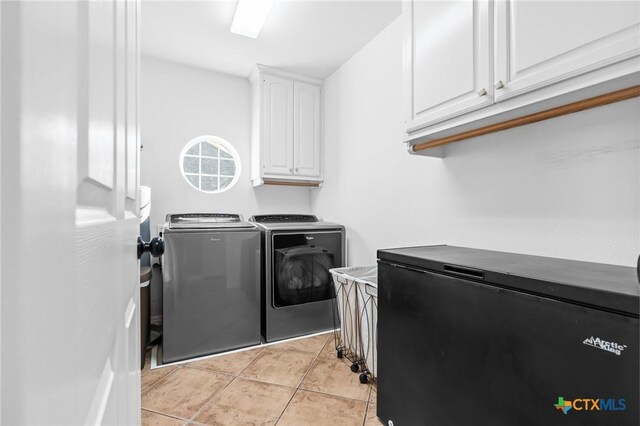 clothes washing area with light tile patterned floors, cabinet space, and washer and clothes dryer