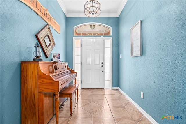 foyer entrance featuring crown molding, light tile patterned floors, a textured wall, baseboards, and a chandelier