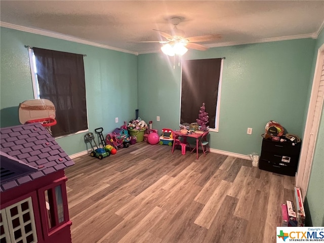 game room with hardwood / wood-style flooring, ceiling fan, and crown molding