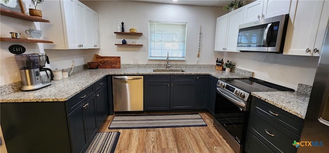 kitchen featuring appliances with stainless steel finishes, sink, white cabinets, and light hardwood / wood-style floors