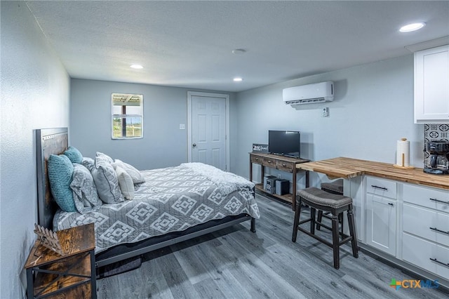 143 S Quailrun Ave, Port Lavaca, TX 77979 - bedroom with a wall mounted air conditioner, wood finished floors, recessed lighting, and a textured ceiling