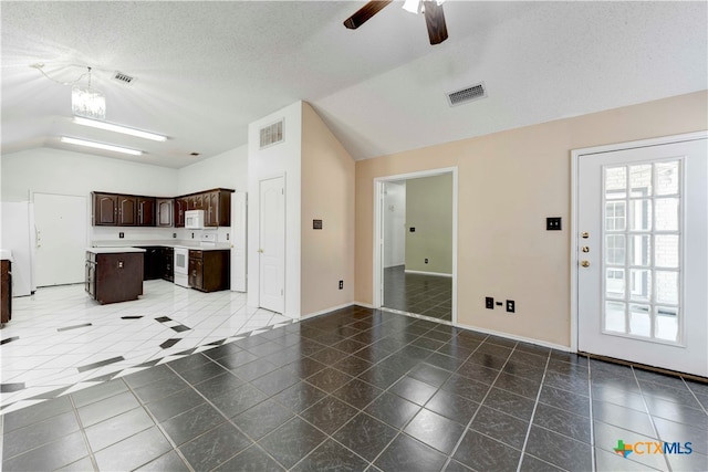 unfurnished living room featuring ceiling fan with notable chandelier, a textured ceiling, vaulted ceiling, and dark tile patterned floors