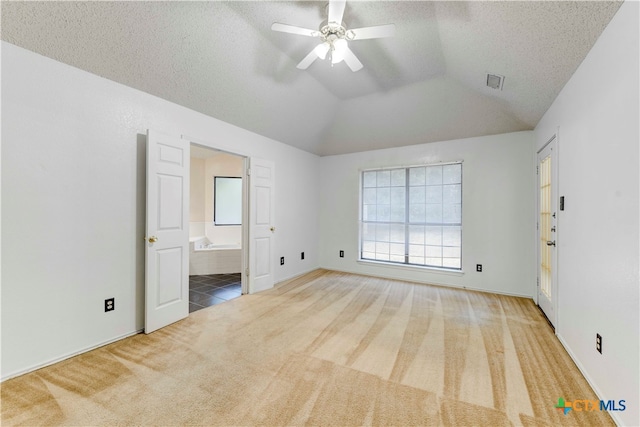 unfurnished bedroom with ceiling fan, a textured ceiling, carpet floors, connected bathroom, and vaulted ceiling