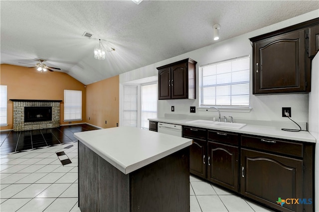 kitchen featuring a textured ceiling, light tile patterned floors, sink, lofted ceiling, and a center island