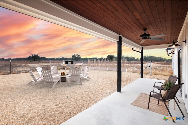 patio terrace at dusk with ceiling fan and an outdoor fire pit