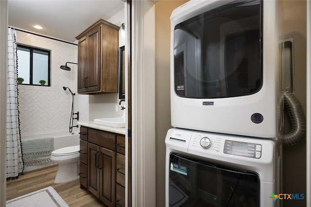 laundry area with stacked washer and clothes dryer, light hardwood / wood-style floors, and sink