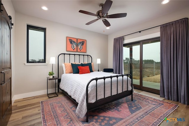 bedroom with access to exterior, hardwood / wood-style floors, a barn door, and ceiling fan