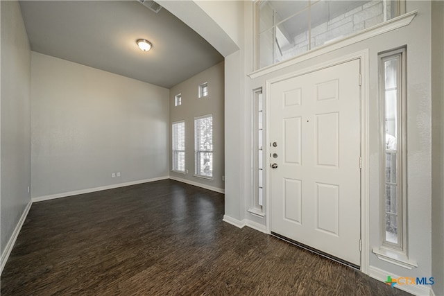 foyer with dark hardwood / wood-style flooring and a towering ceiling