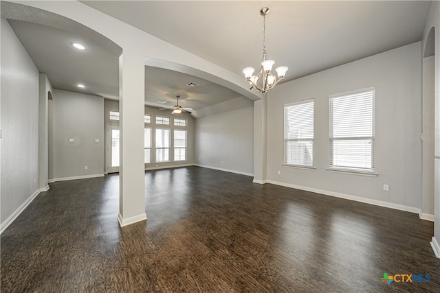 spare room featuring dark wood-type flooring and ceiling fan with notable chandelier