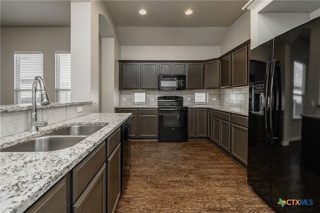 kitchen featuring black appliances, light stone counters, dark hardwood / wood-style flooring, decorative backsplash, and sink