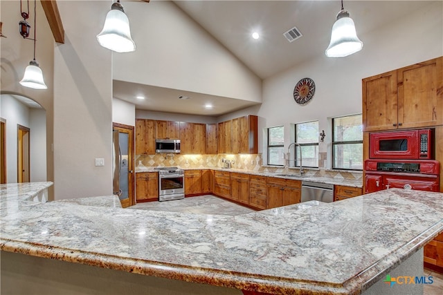 kitchen with stainless steel appliances, sink, tasteful backsplash, high vaulted ceiling, and pendant lighting