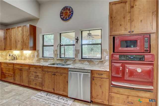 kitchen with sink, stainless steel dishwasher, decorative backsplash, and light stone countertops