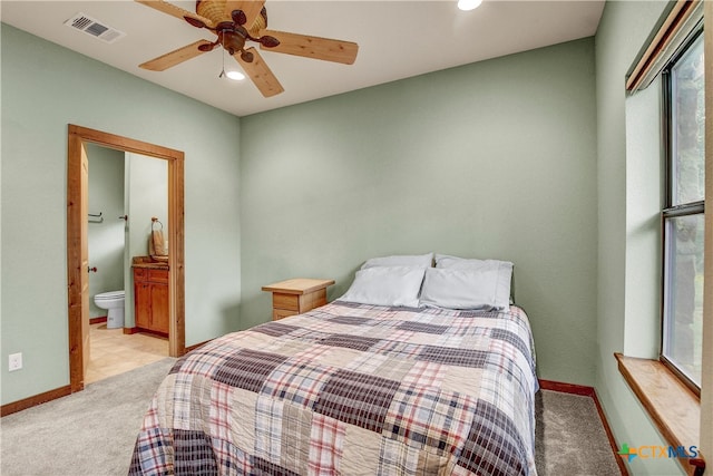 bedroom with ceiling fan, connected bathroom, and light colored carpet